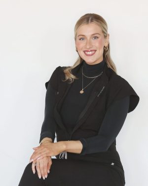 Smiling woman in black top with layered necklaces and earrings. Smiling woman in black top with layered necklaces and earrings.