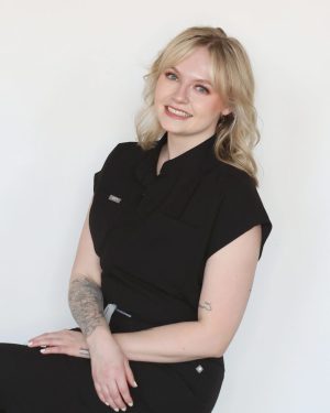 Smiling woman with blonde hair in a black outfit posing against a white background. Smiling woman with blonde hair in a black outfit posing against a white background.