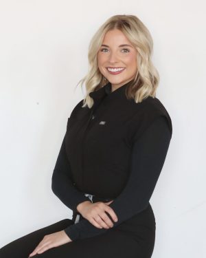 Smiling woman in a black long-sleeve shirt against a white background. Smiling woman in a black long-sleeve shirt against a white background.
